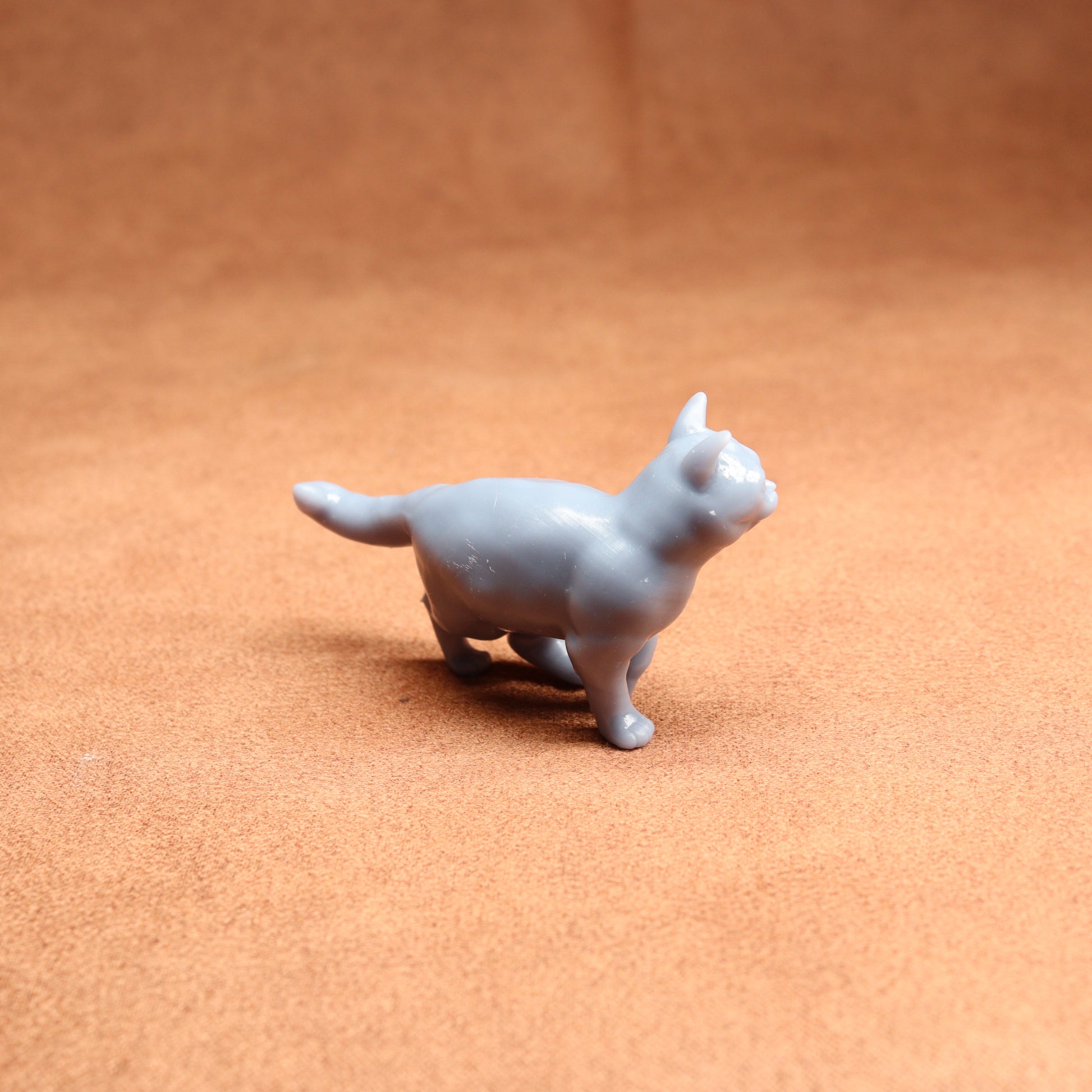 Gray cat figurine on a brown surface