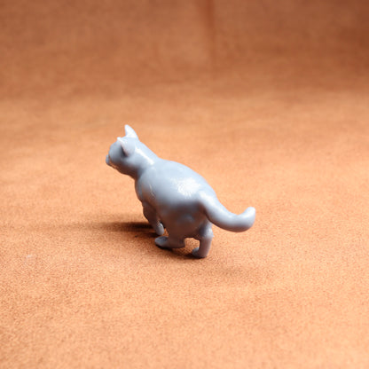 Small gray cat figurine on a brown surface