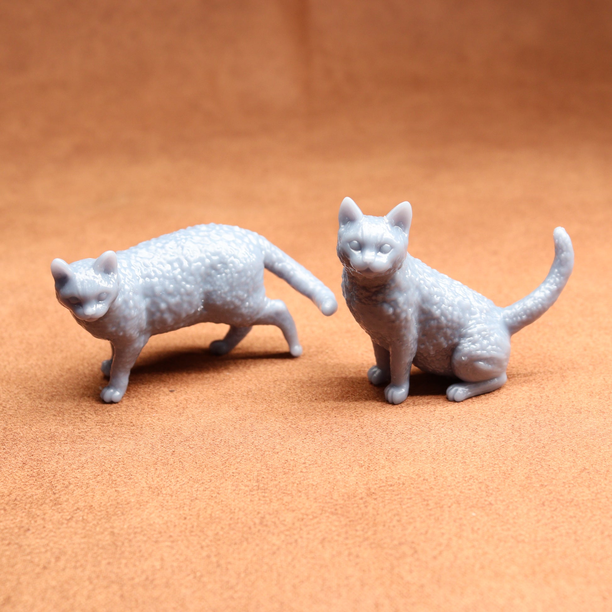 Two gray cat figurines on a brown surface