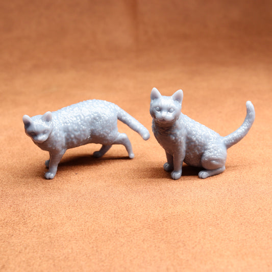 Two gray cat figurines on a brown surface