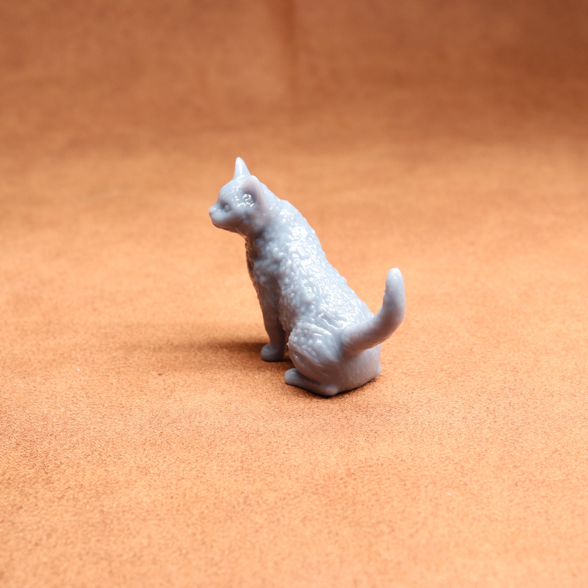 Small white cat figurine on a brown surface