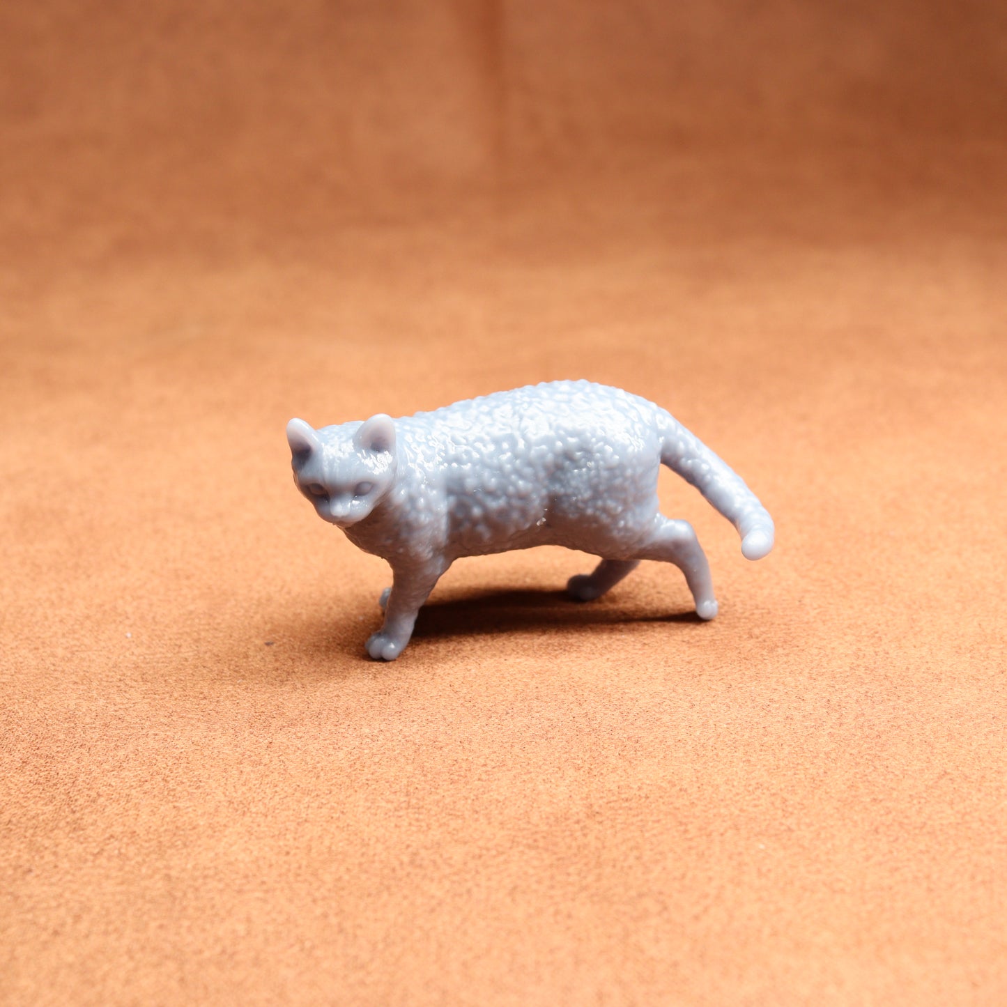 Small gray cat figurine on a brown surface