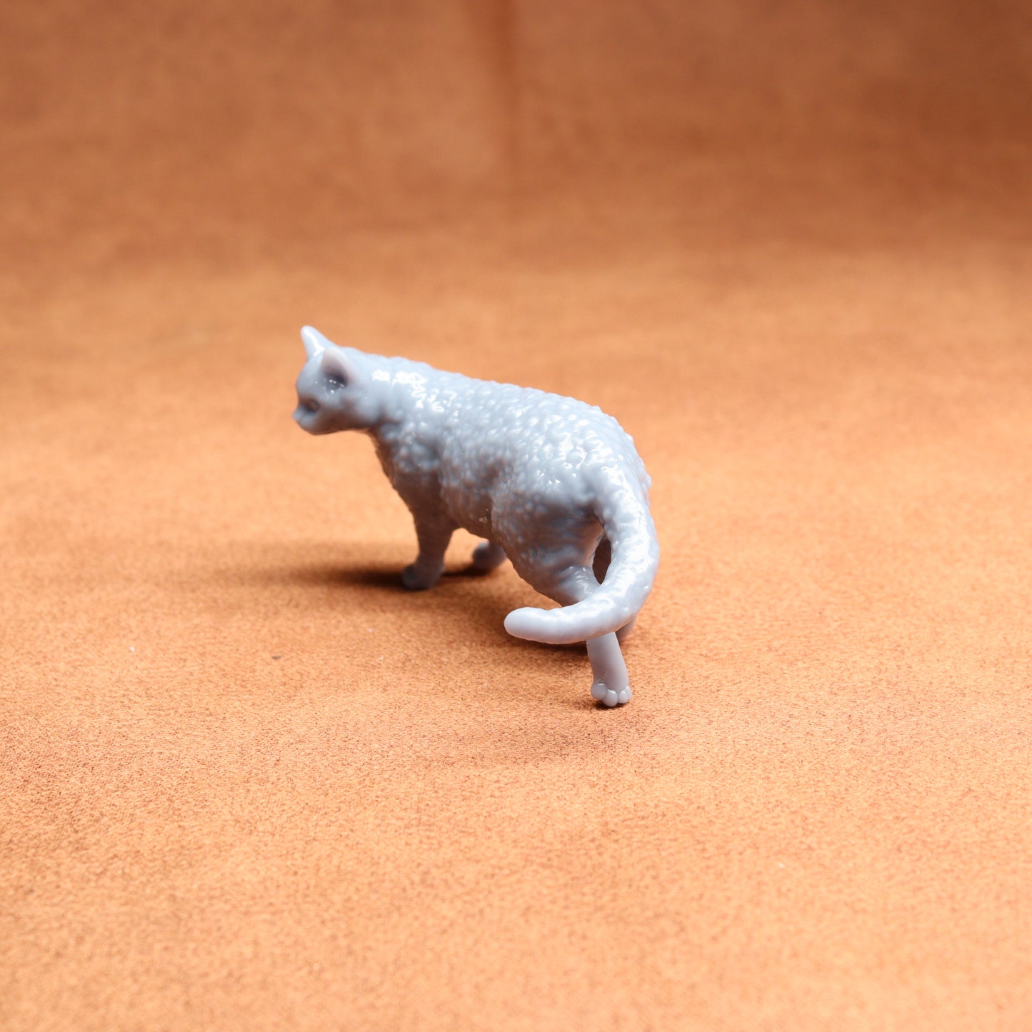 Small gray cat figurine on a brown surface