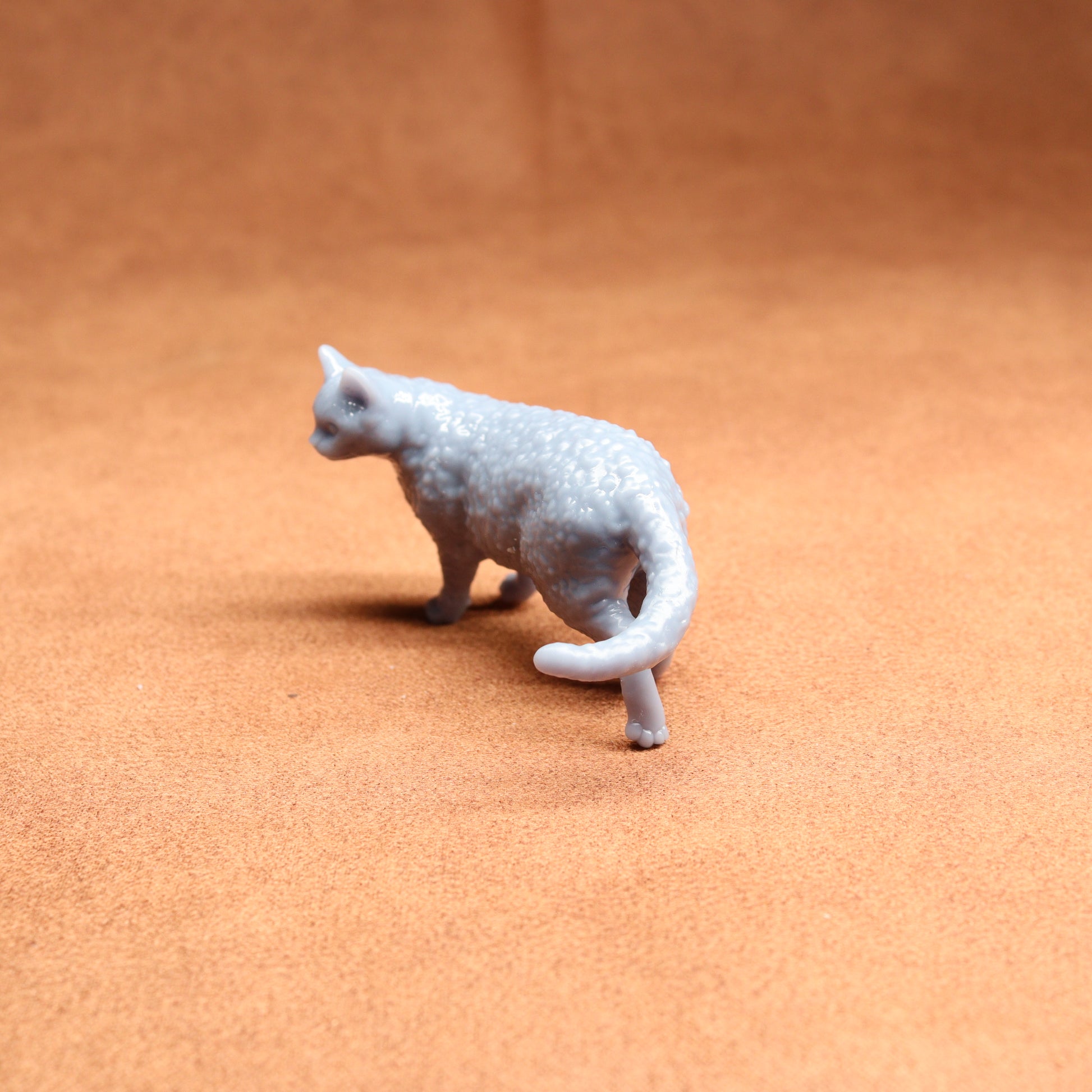 Small gray cat figurine on a brown surface
