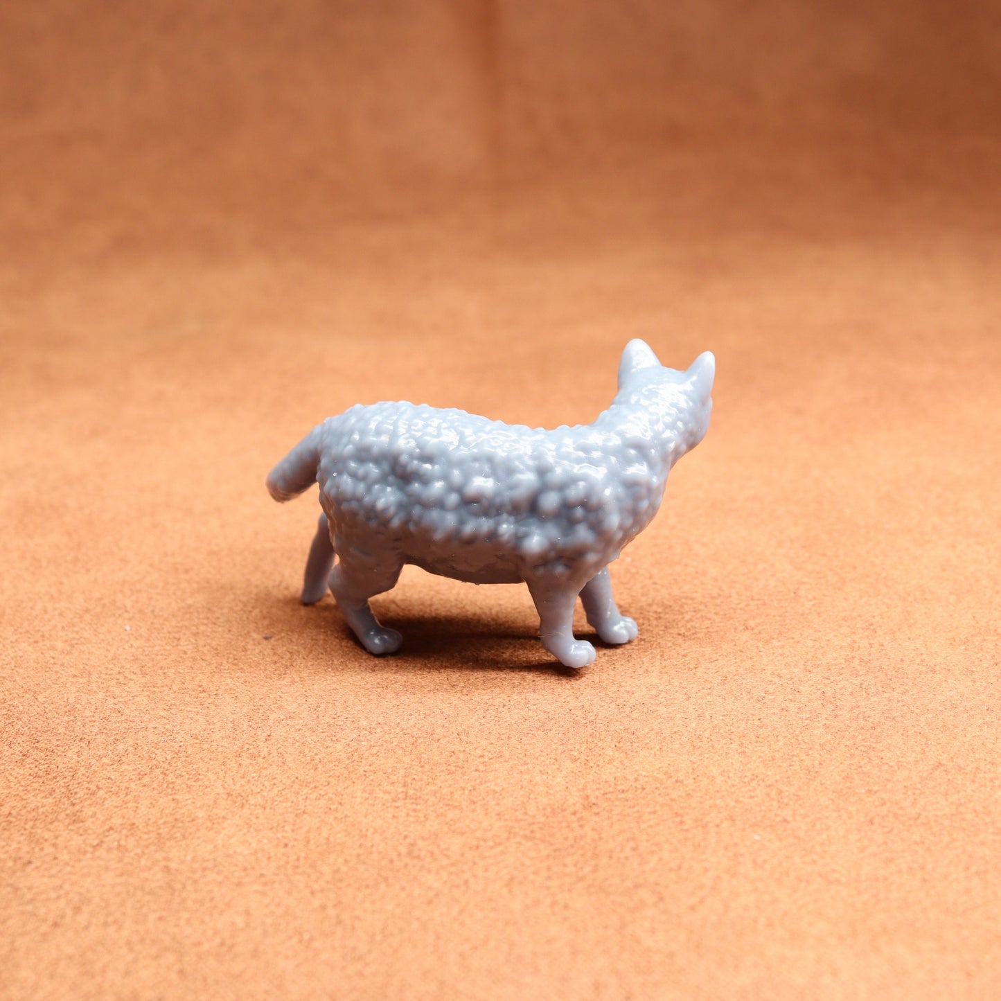 Small gray textured animal figurine on a brown surface