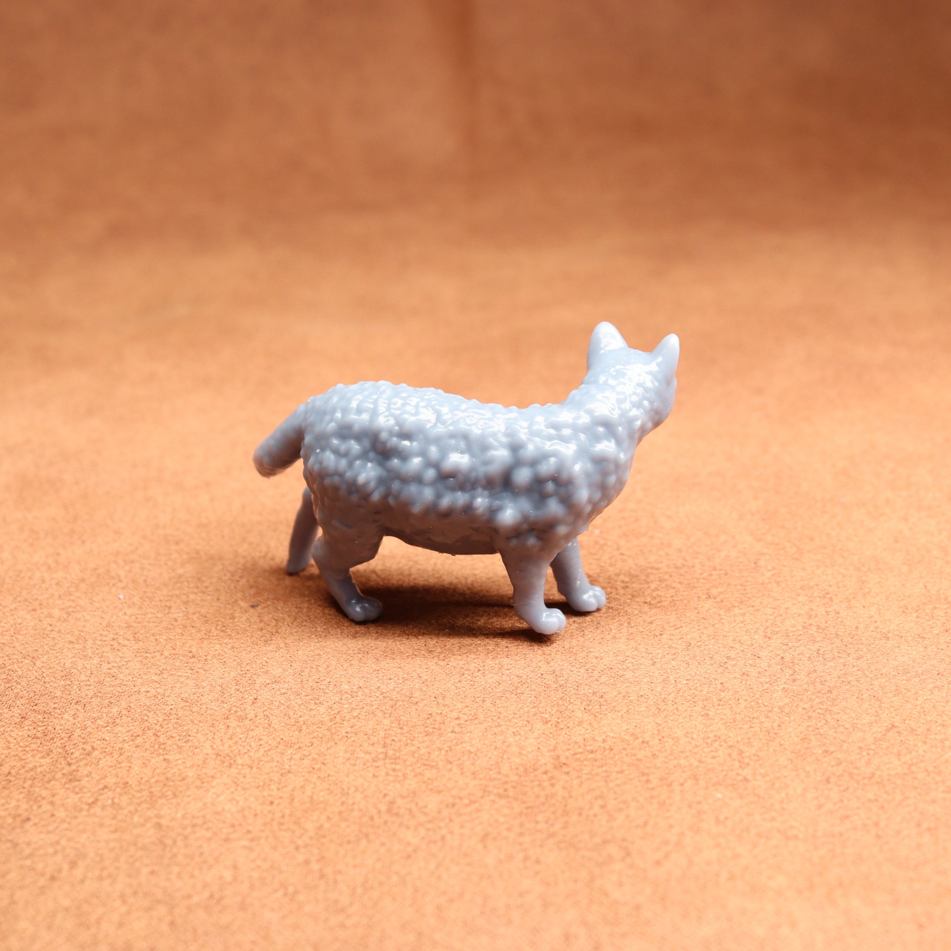 Small gray textured animal figurine on a brown surface