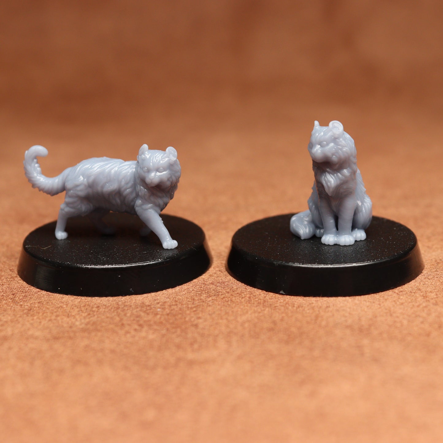 Two white cat figurines on black bases against a brown background