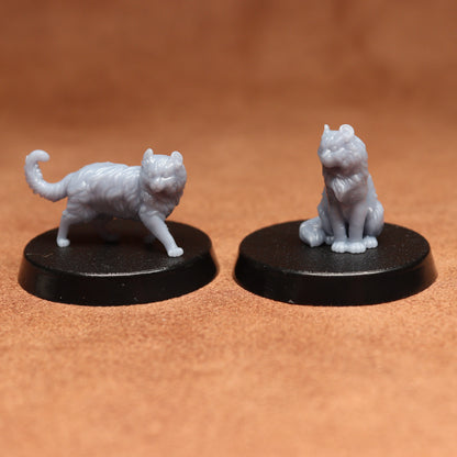 Two white cat figurines on black bases against a brown background