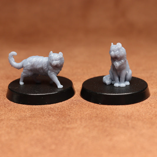 Two white cat figurines on black bases against a brown background