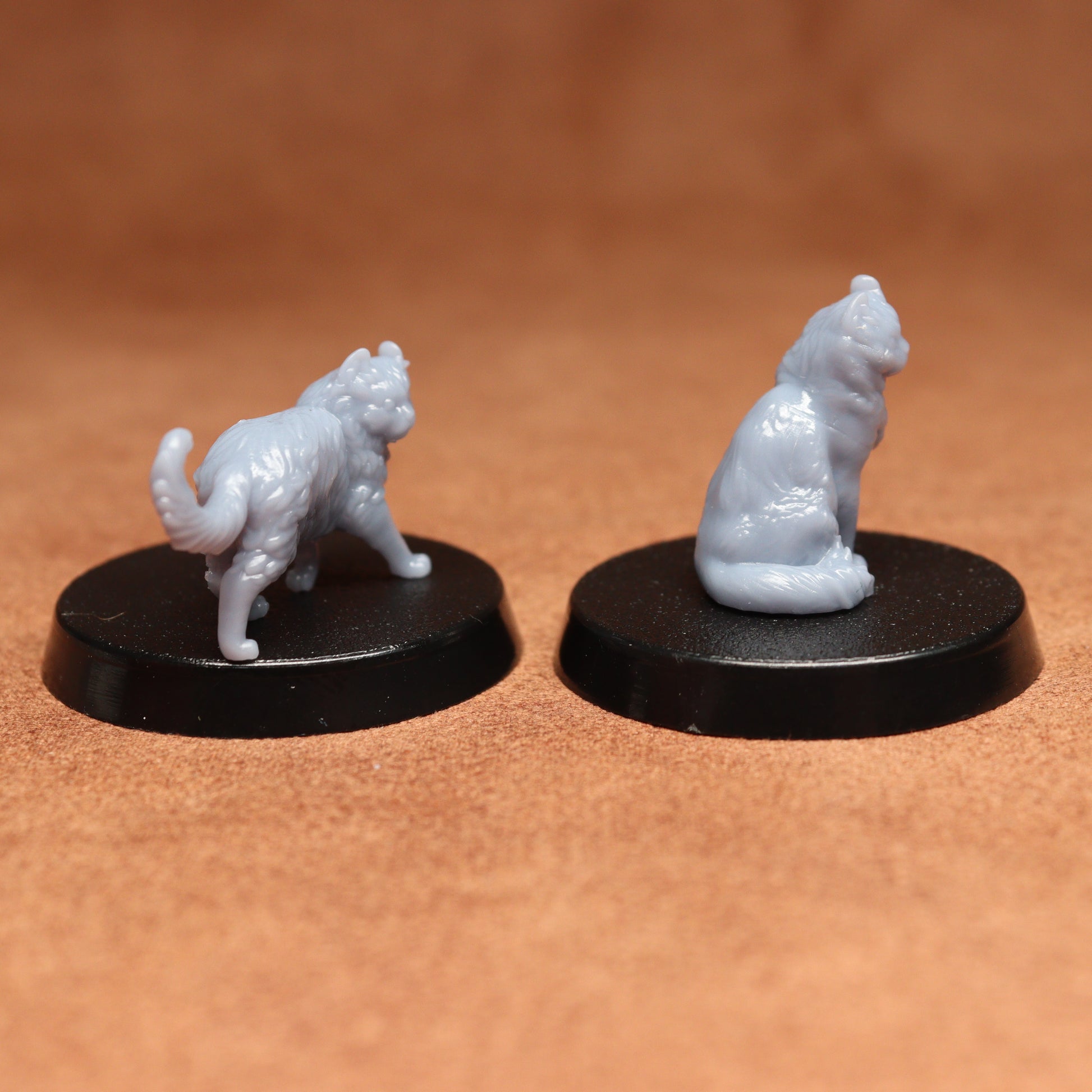 Two white cat figurines on black bases against a brown background