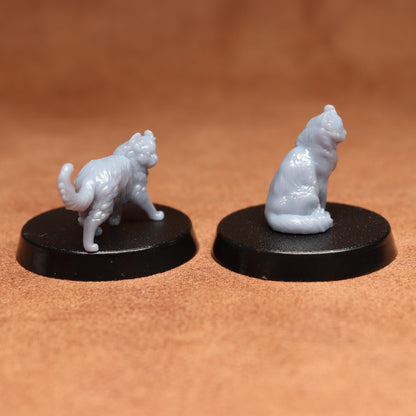 Two white cat figurines on black bases against a brown background