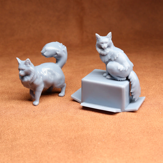 Two white cat figurines on an orange surface