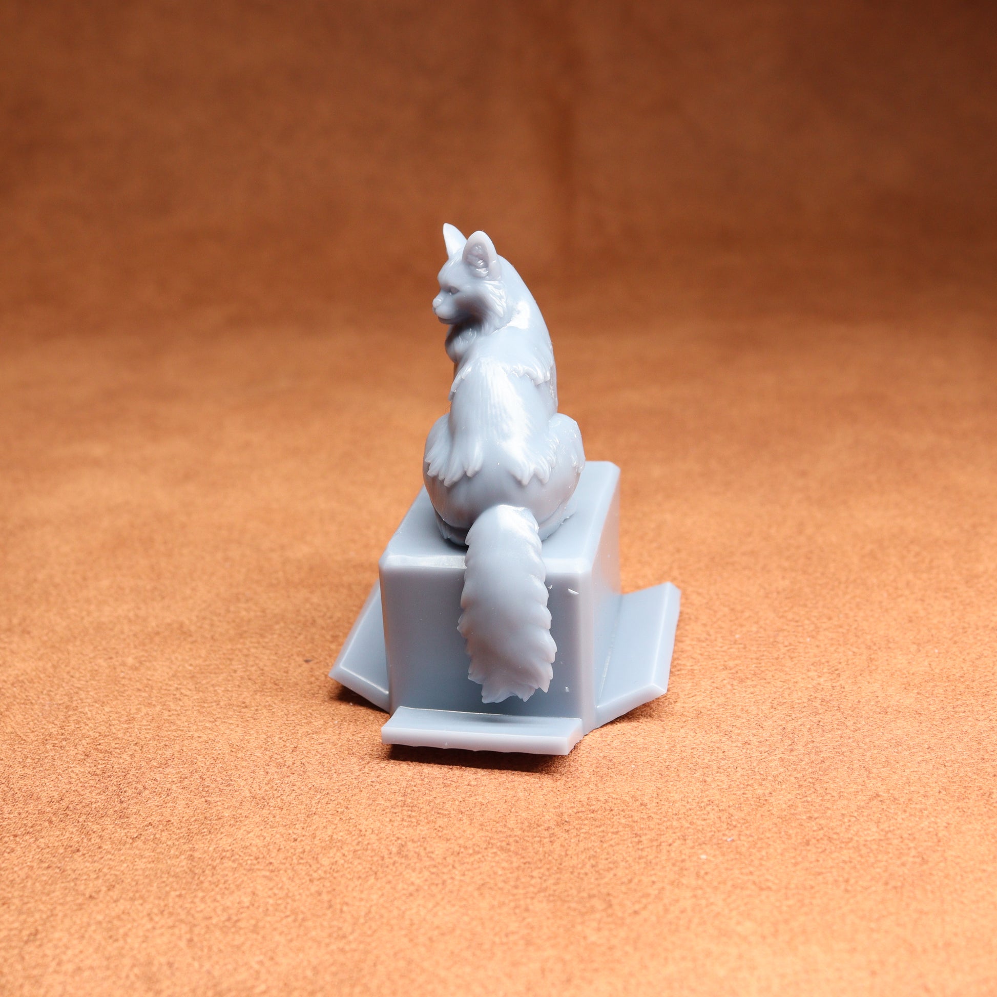 White ceramic cat figurine on a square base against an orange background