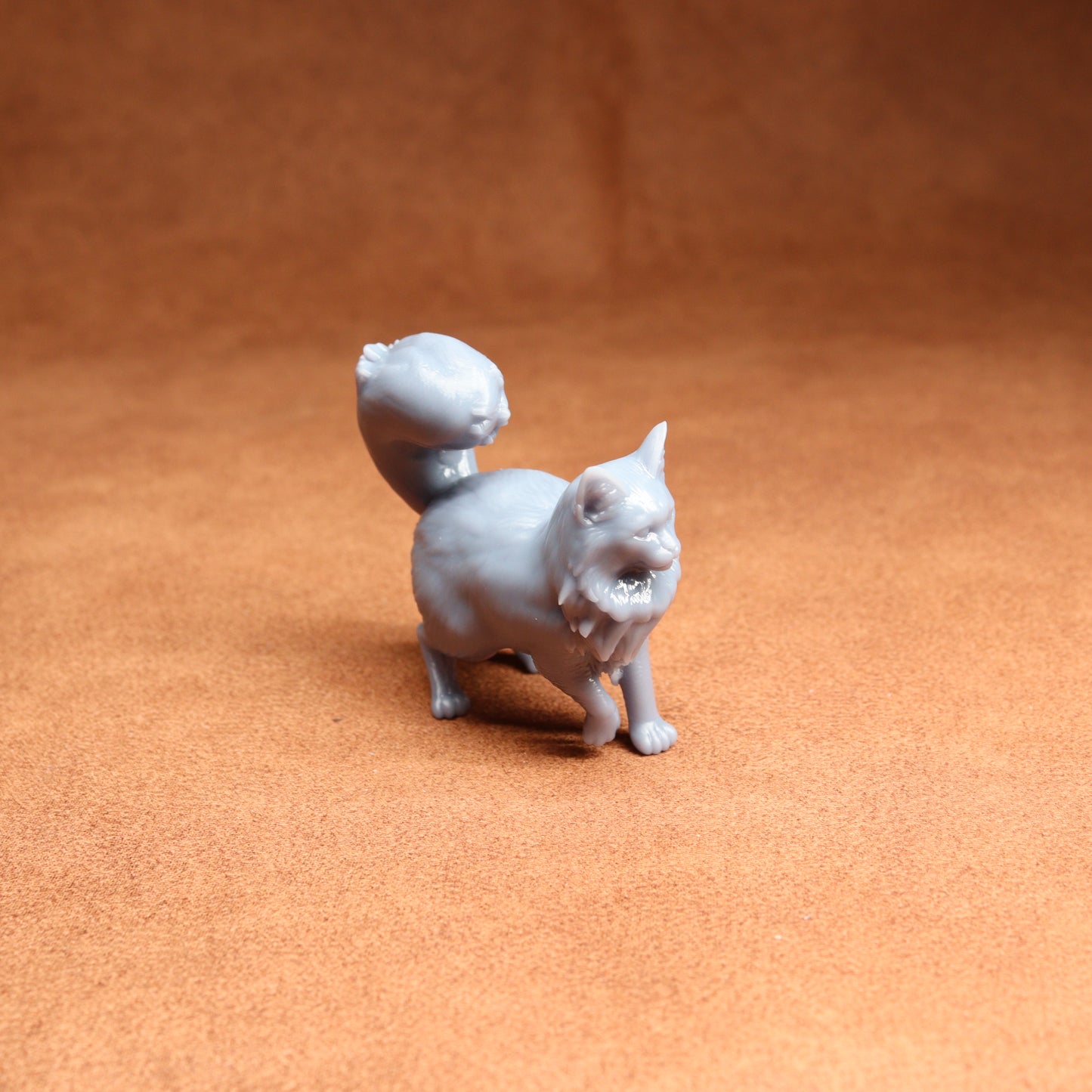 Small gray cat figurine on a brown surface