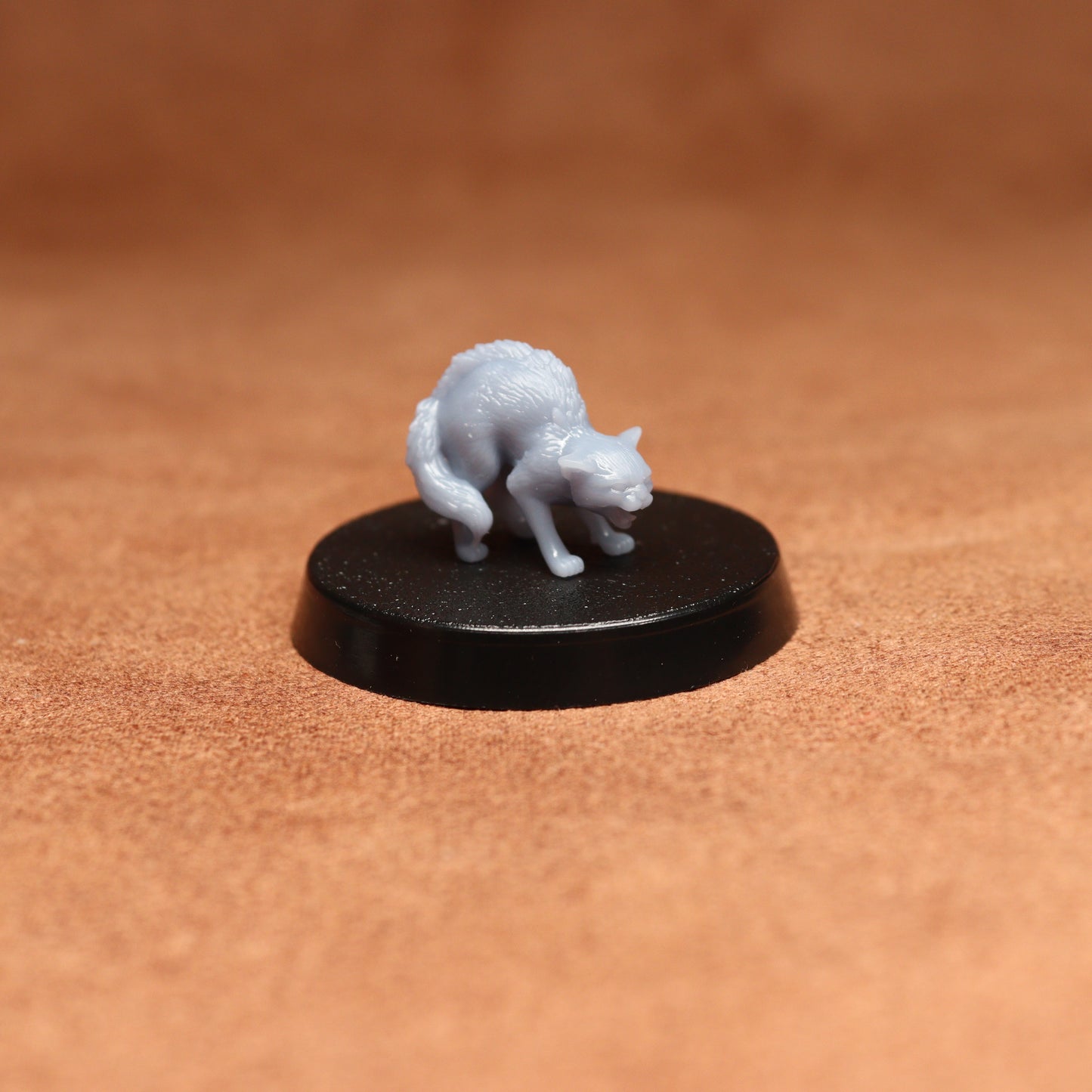Small white figurine on a black base against a brown background
