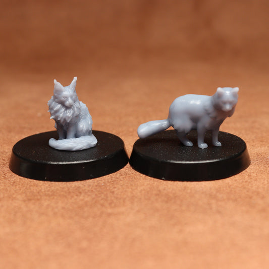 Two miniature catfigurines on black bases against a brown background