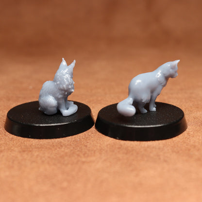 Two white cat figurines on black bases against a brown background
