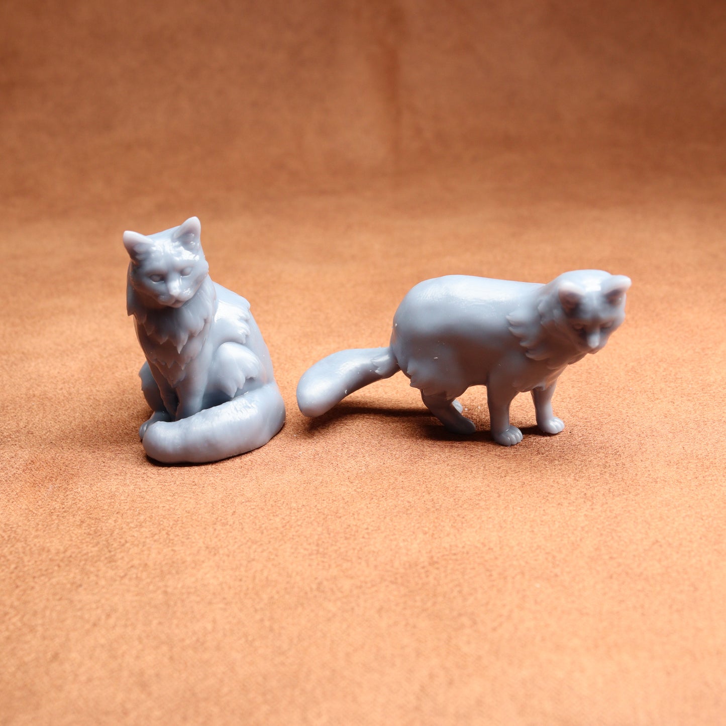 Two gray cat figurines on a brown surface