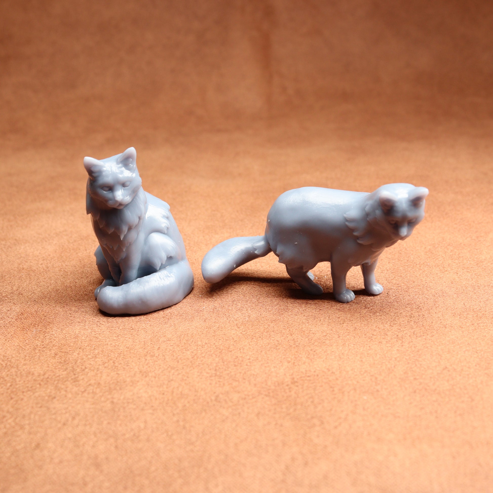 Two gray cat figurines on a brown surface