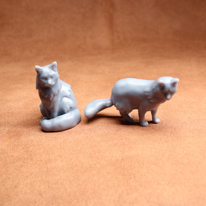 Two gray cat figurines on a brown surface
