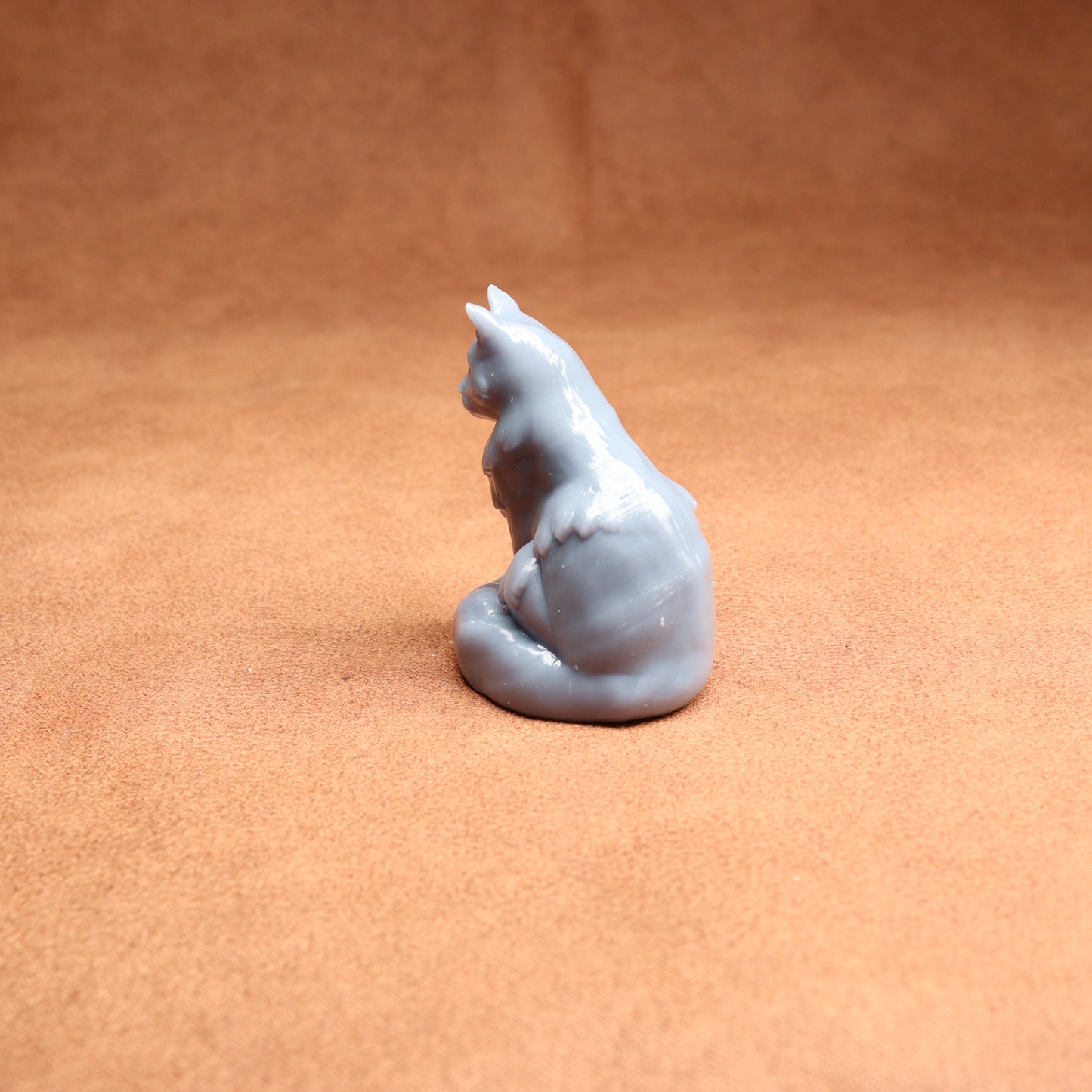 Gray cat-shaped candle on a brown surface