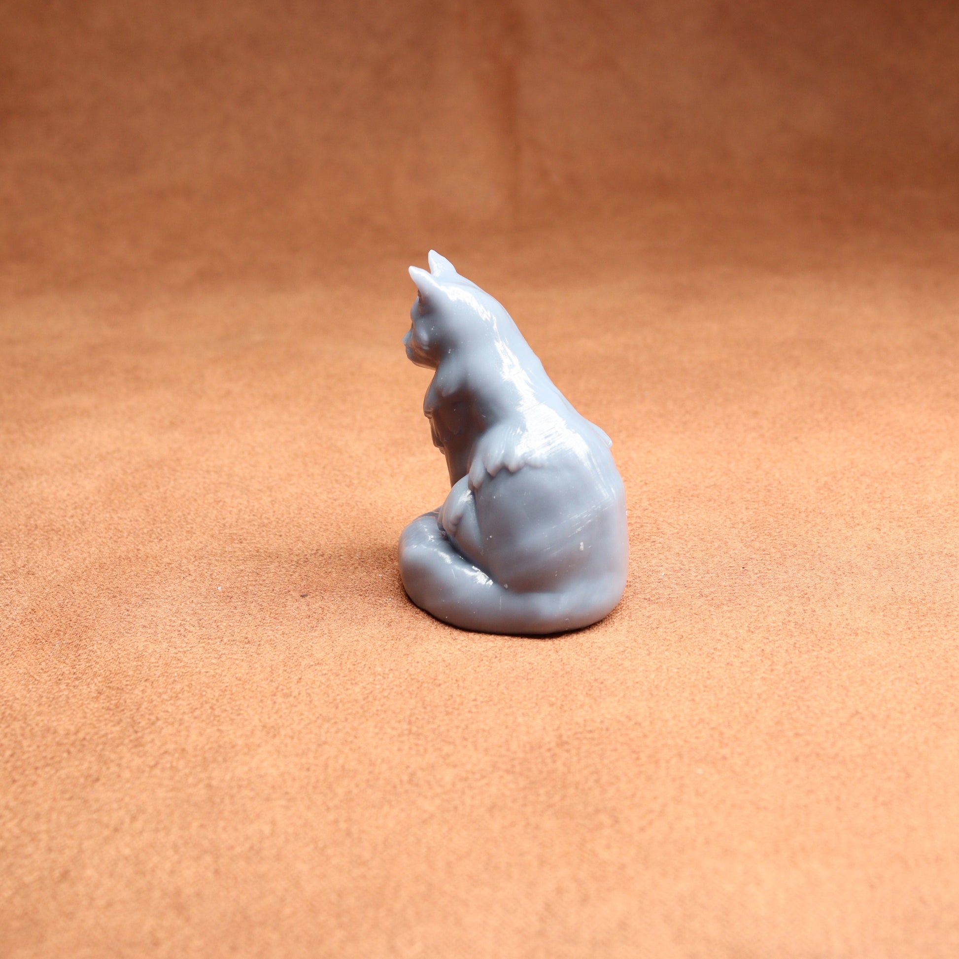 Gray cat-shaped candle on a brown surface