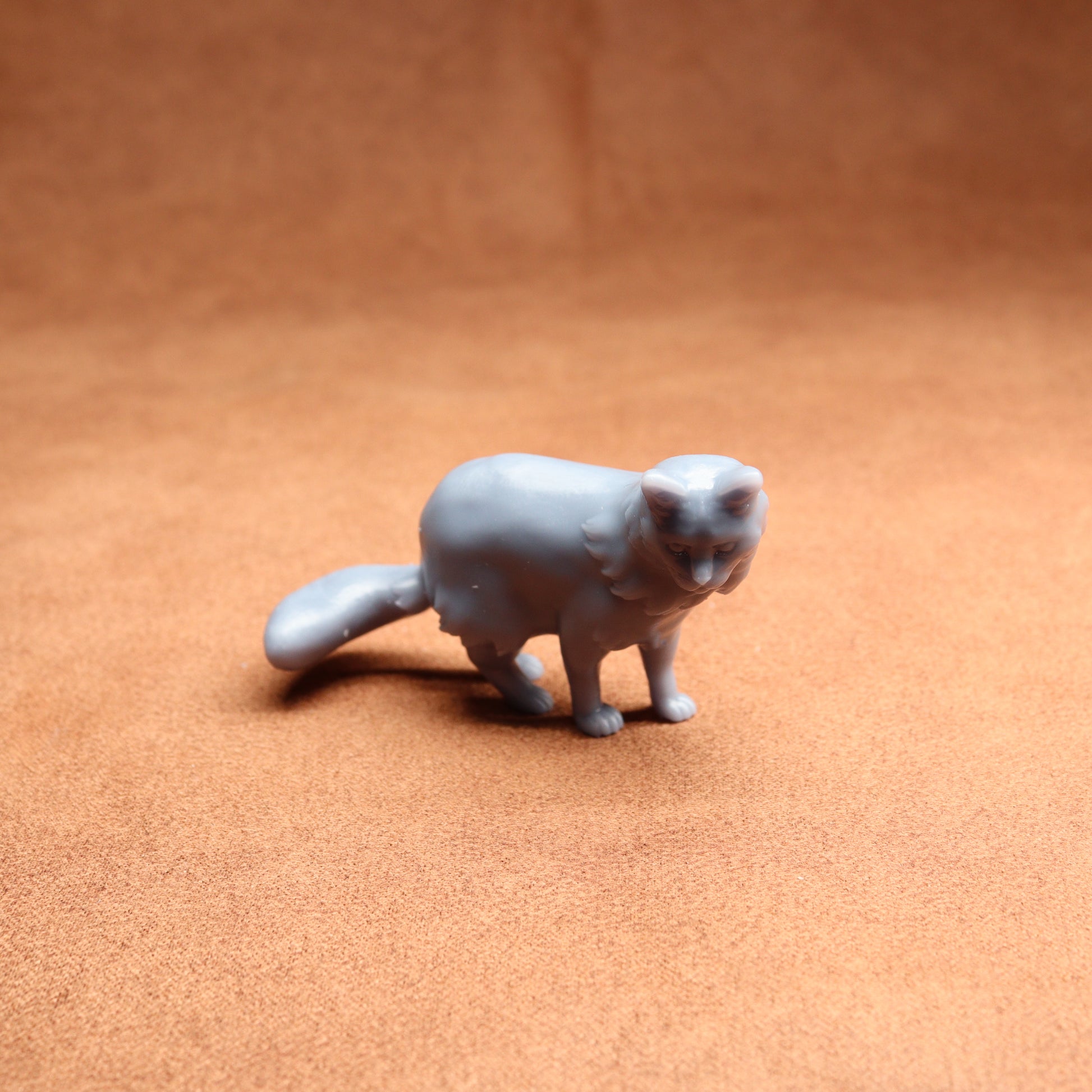Gray cat figurine on a brown surface