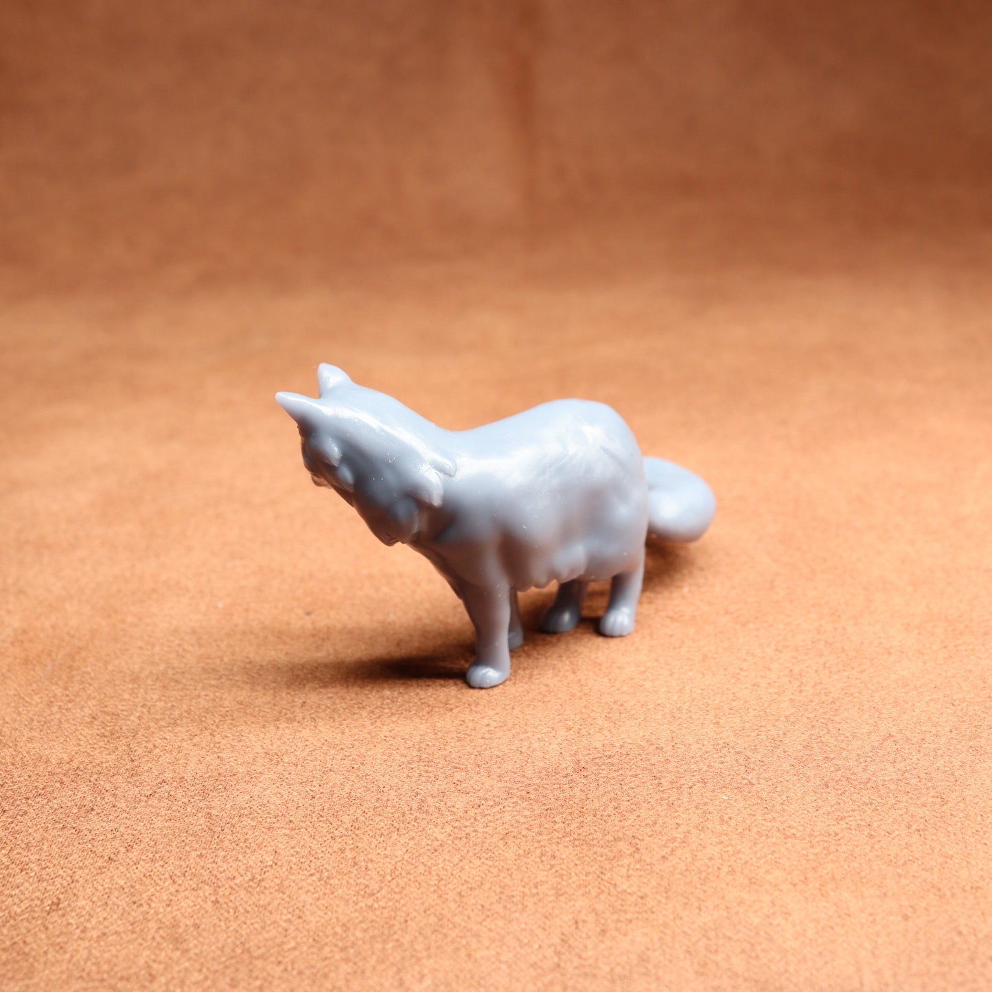 Small gray dog figurine on a brown surface