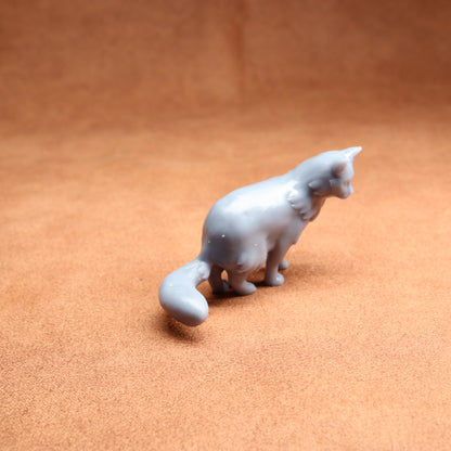 White ceramic cat figurine on a brown surface