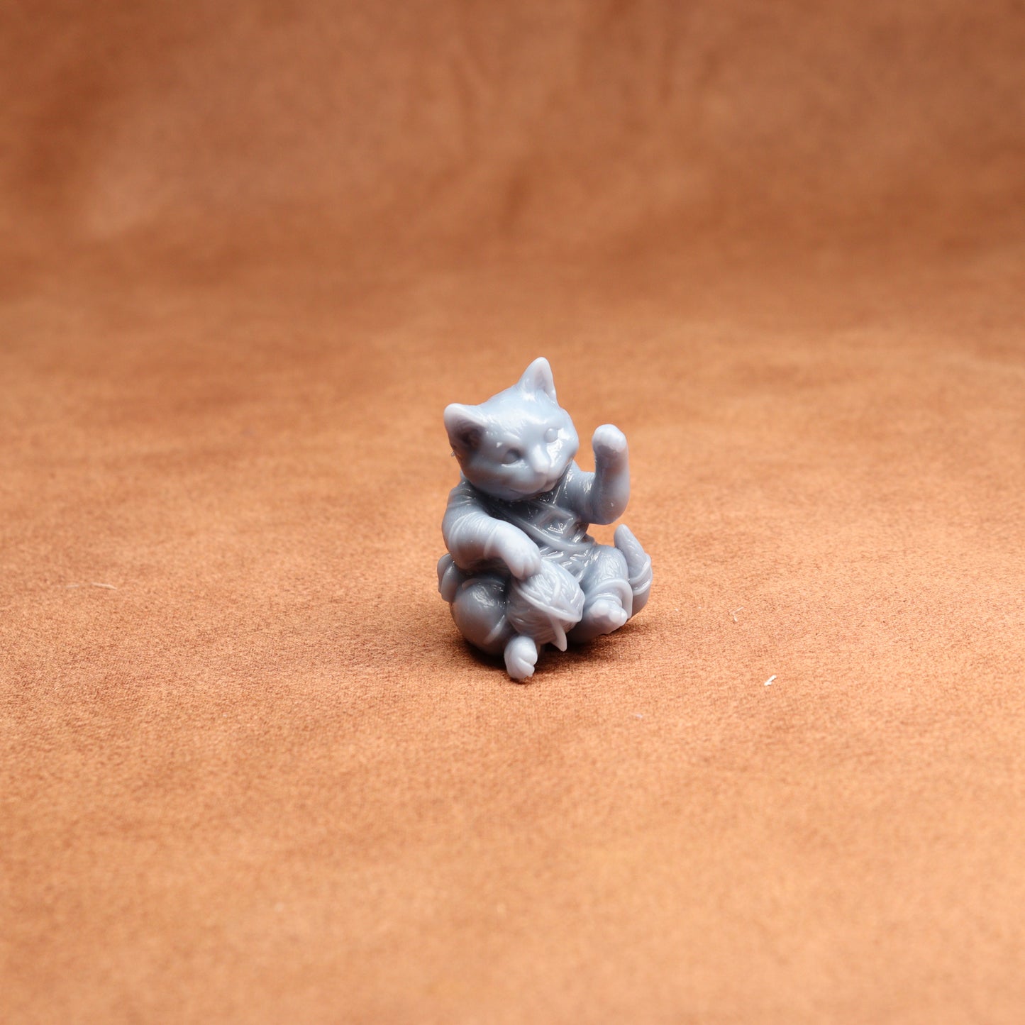 Small gray cat figurine on a brown surface