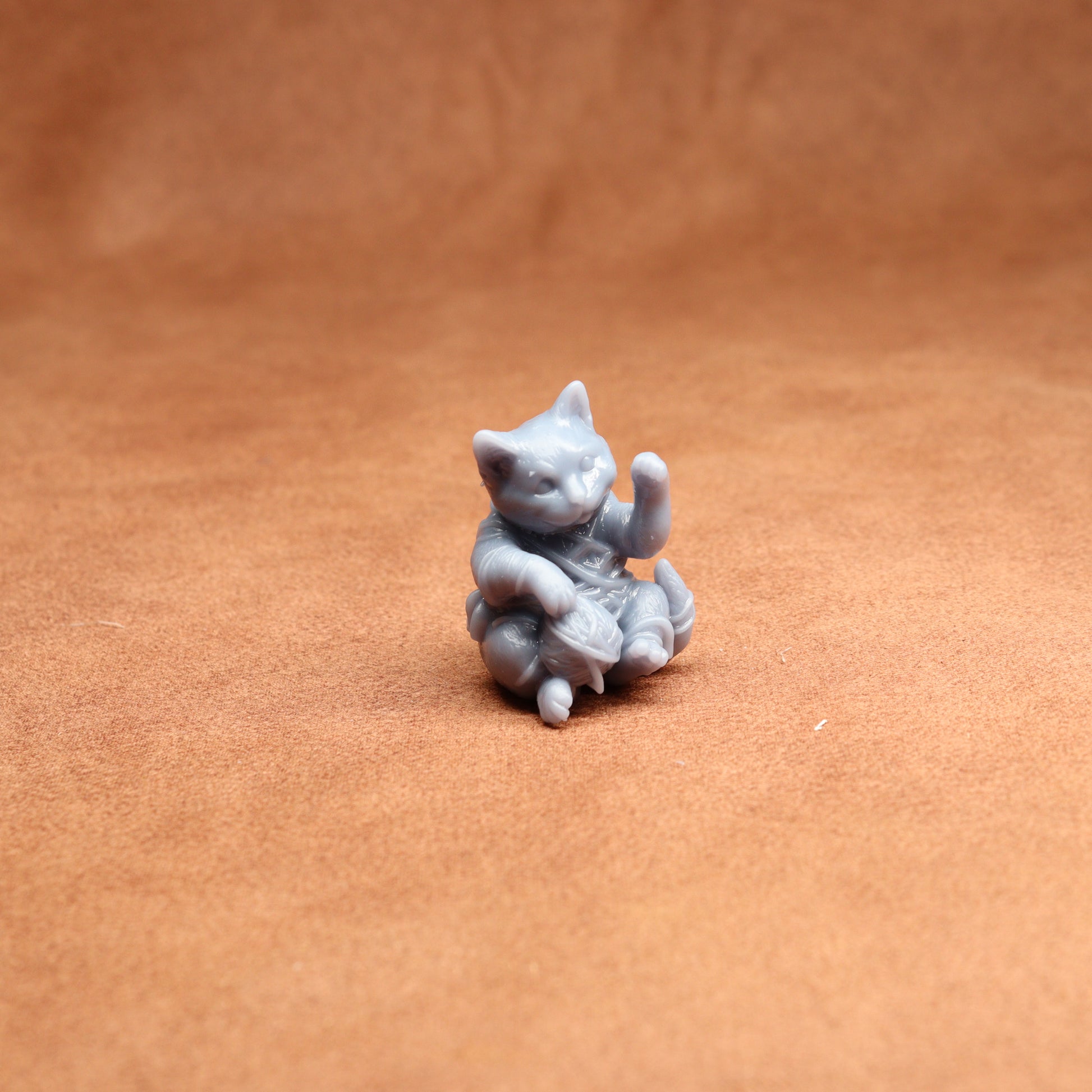Small gray cat figurine on a brown surface