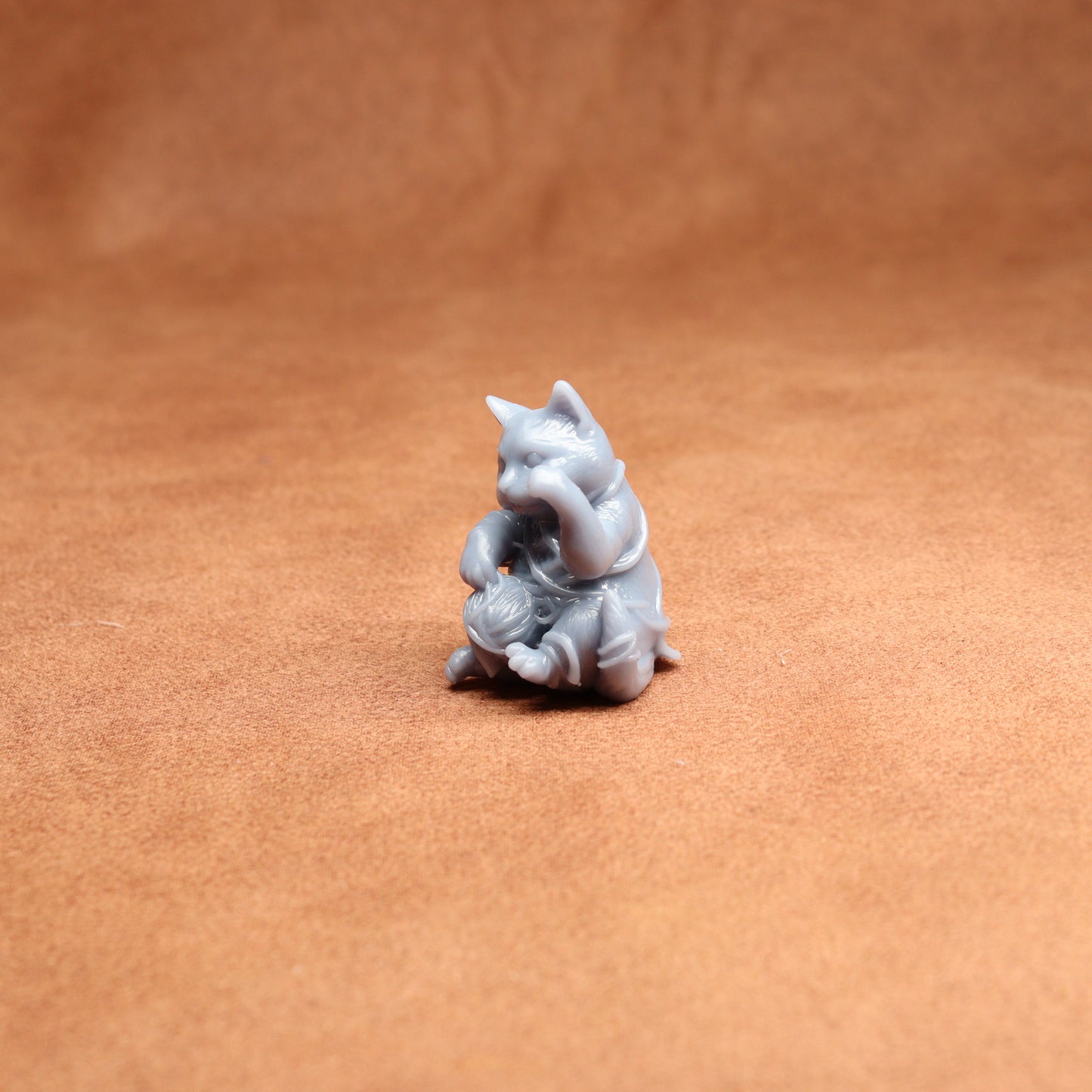 Small gray figurine of a cat on a brown surface