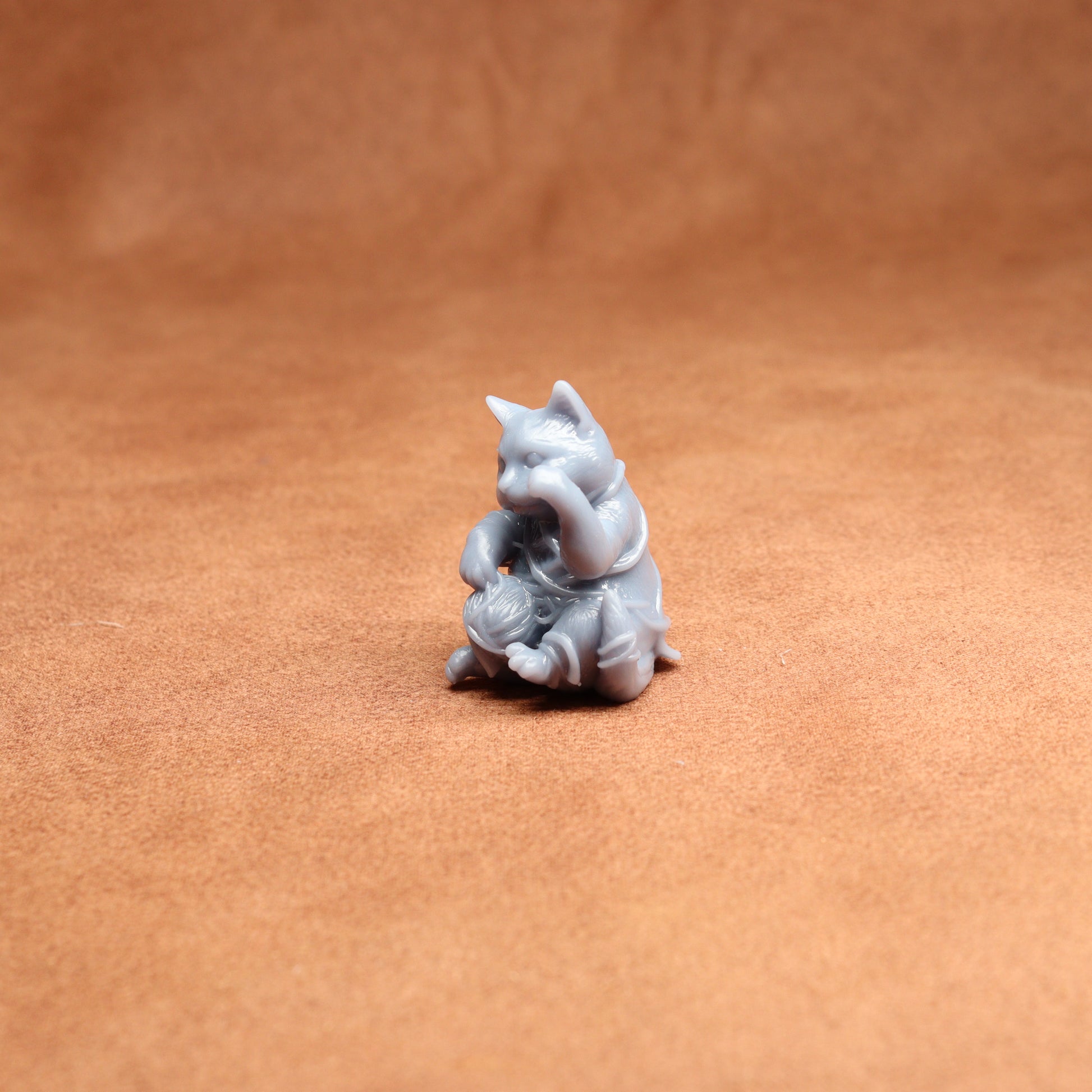 Small gray figurine of a cat on a brown surface