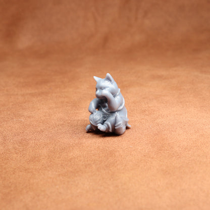 Small gray figurine of a cat on a brown surface
