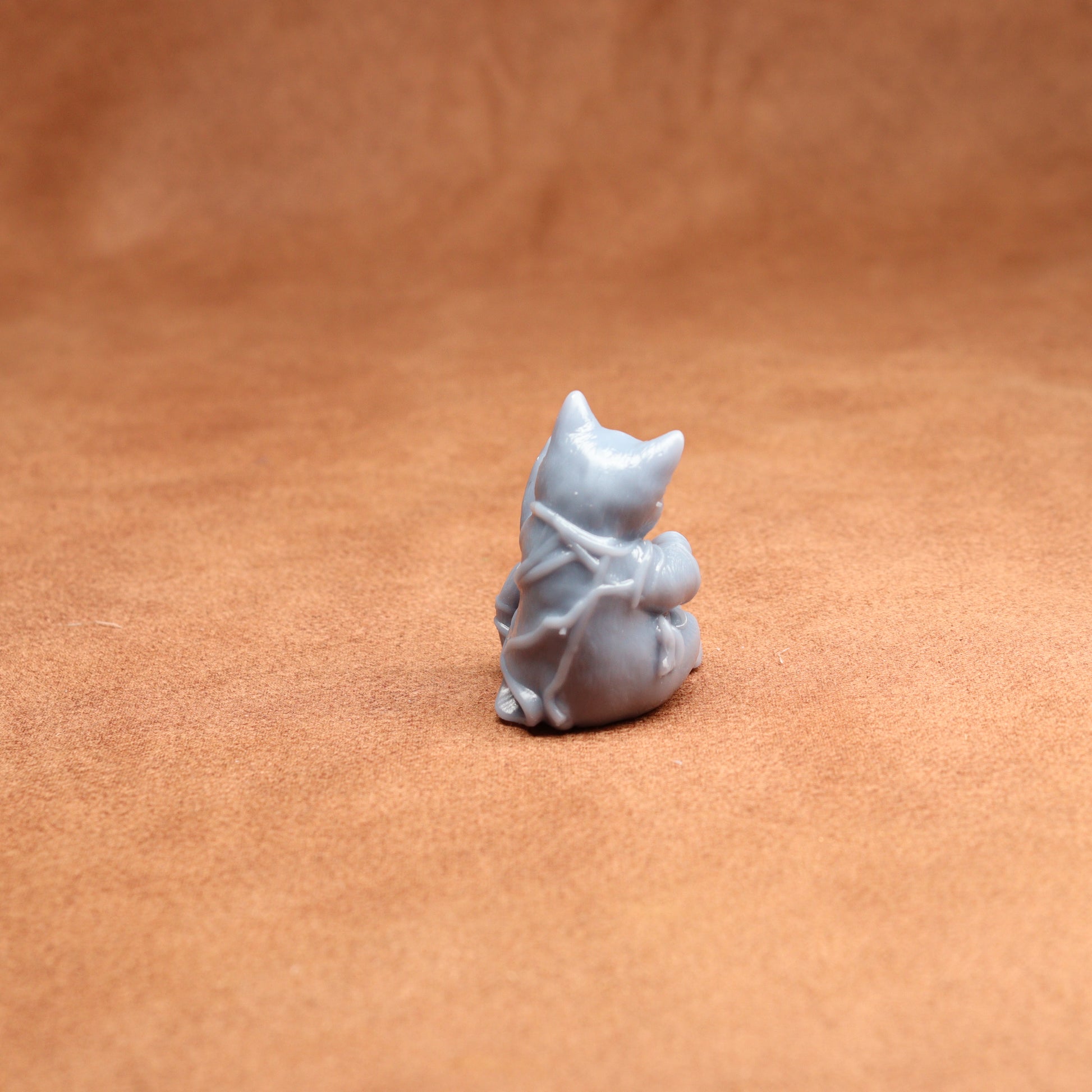 Small white resin cat figurine on a brown leather surface