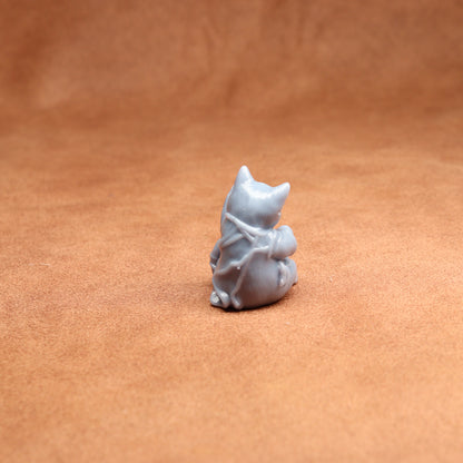 Small white resin cat figurine on a brown leather surface