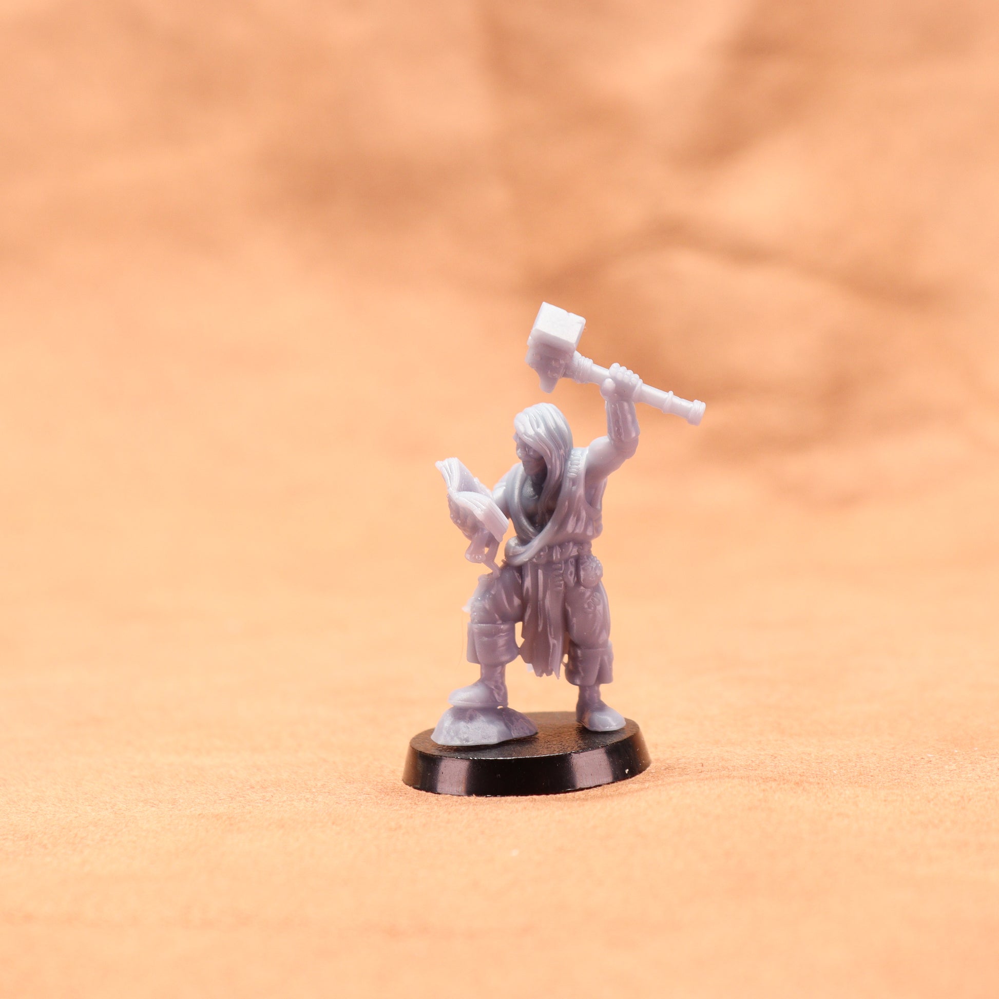Miniature figurine of a warrior holding a hammer on an orange background