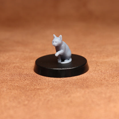 grey resin miniature cat figure on a black base with a brown background