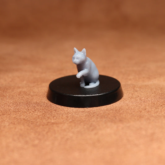 grey resin miniature cat figure on a black base with a brown background