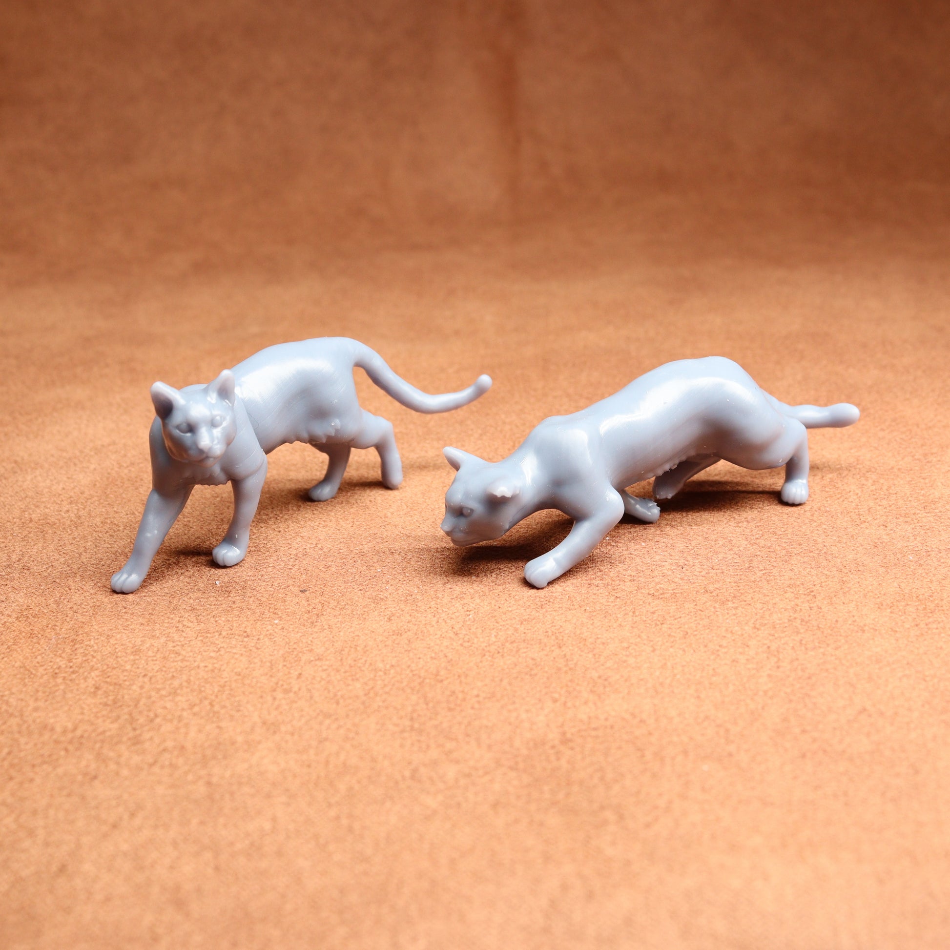 Two white cat figurines on a brown surface