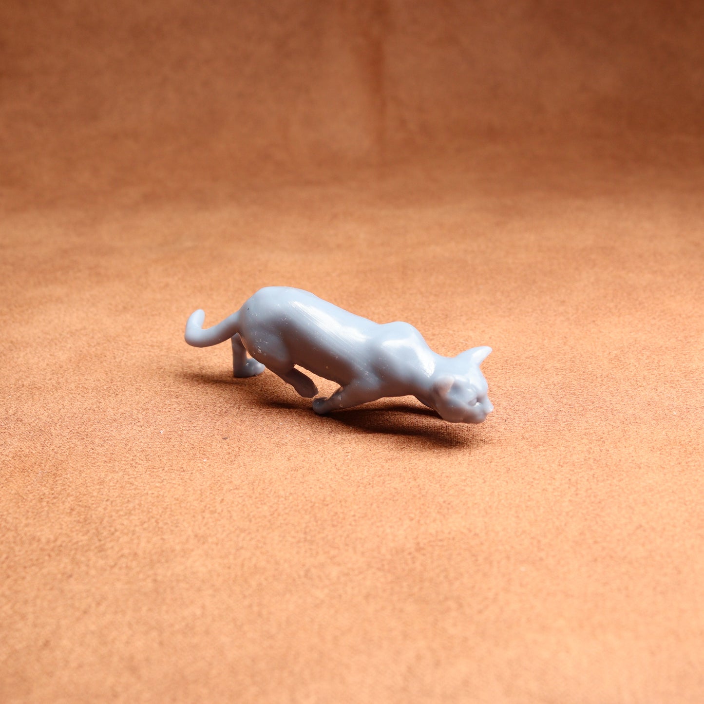 Small gray cat figurine on a brown surface