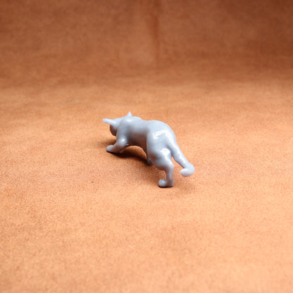 stooped cat figurine on a brown background