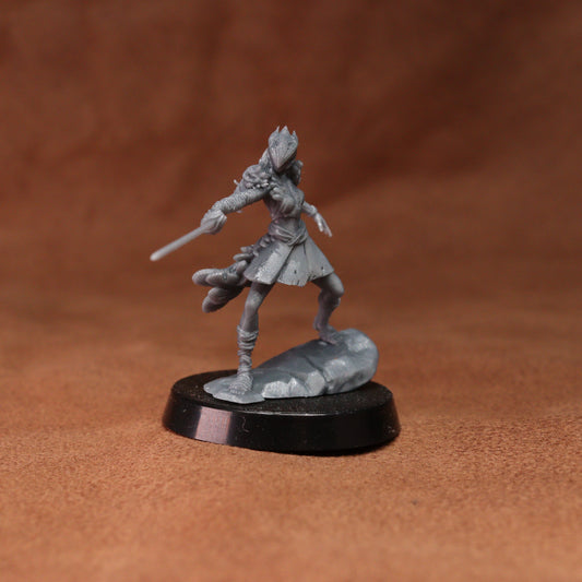A gray unpainted fantasy miniature figurine of a warrior holding a sword, standing on a black circular base against a warm brown textured background.