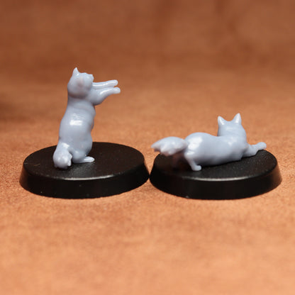 Two white cat figurines on black bases against a brown background