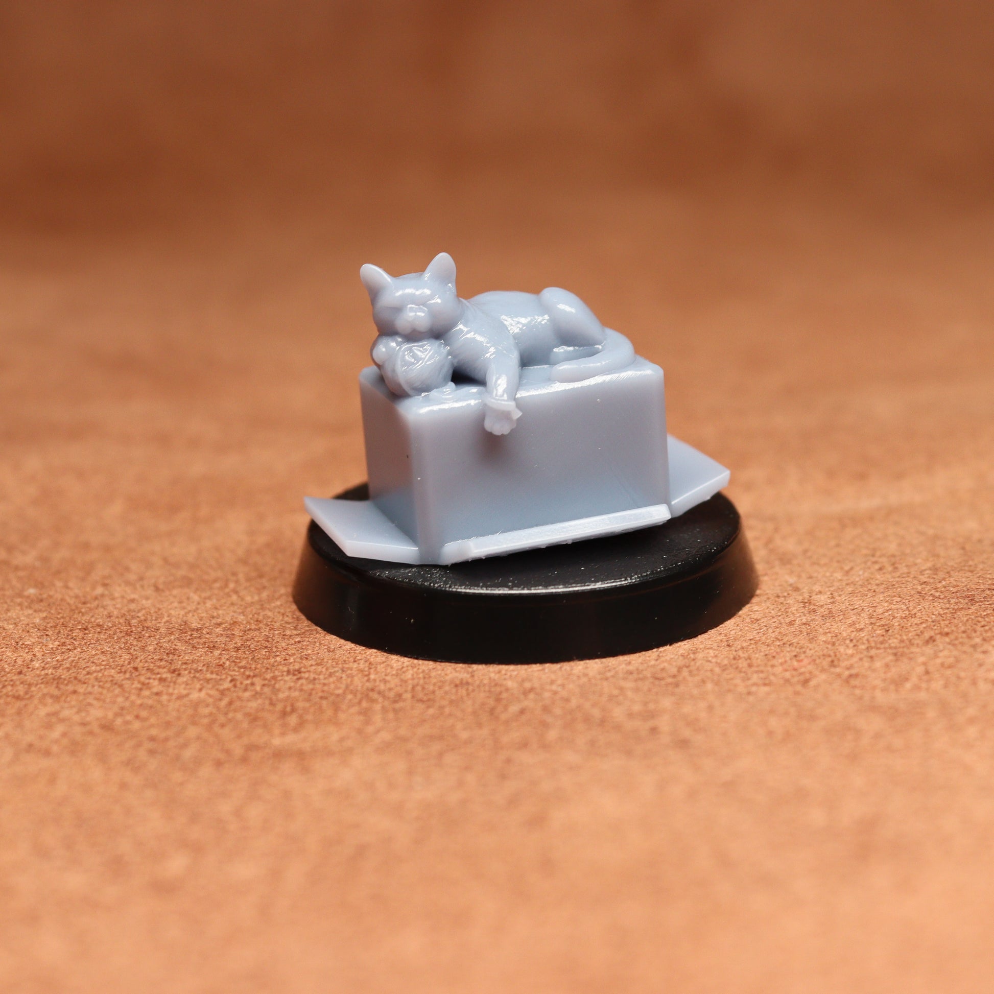 Small figurine of a cat on a box with a brown background