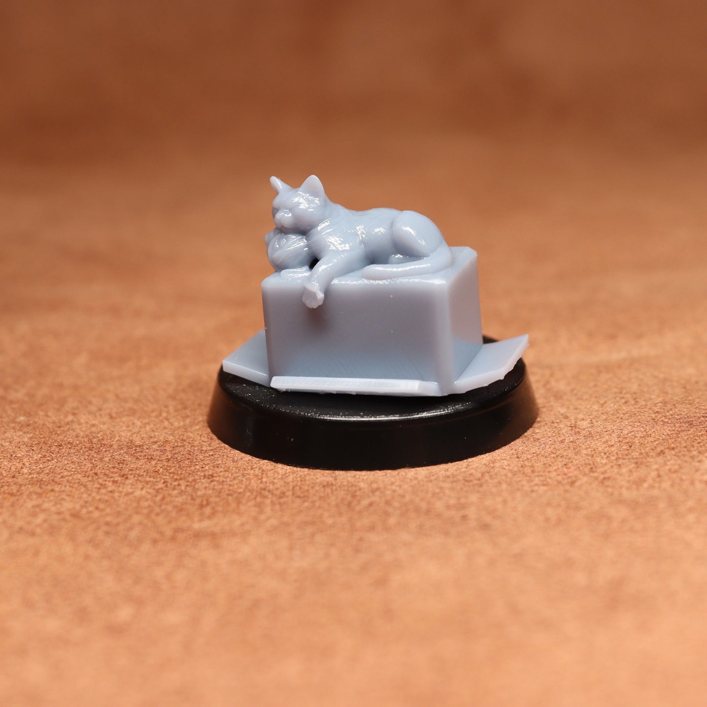 Small white ceramic figurine of a cat on a pedestal against a brown background