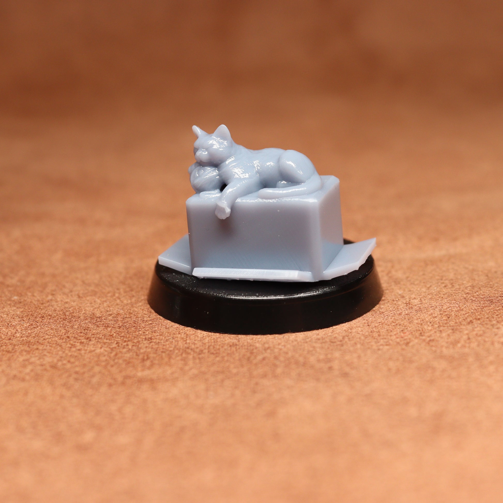 Small white ceramic figurine of a cat on a pedestal against a brown background