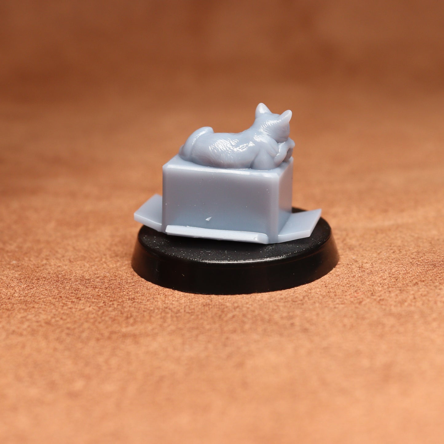 Small white figurine of a cat on a black base against a brown background