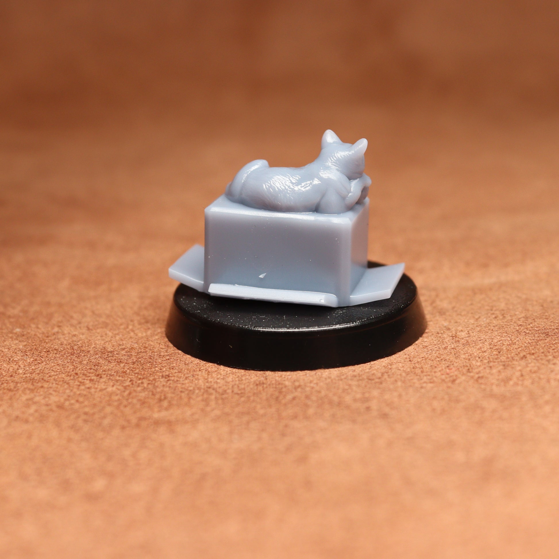 Small white figurine of a cat on a black base against a brown background