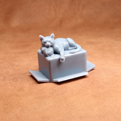 Gray cat figurine laid on a box against a brown background